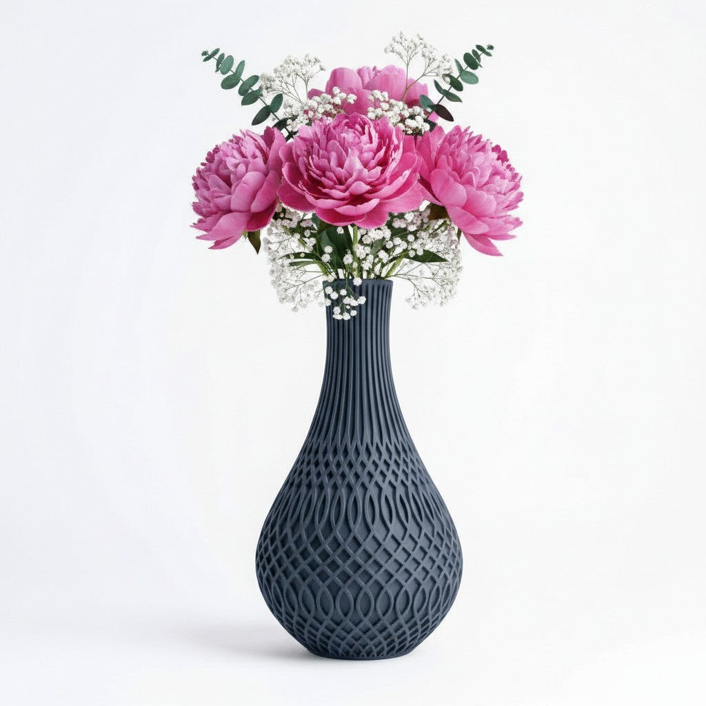 Inflect Vase in dark grey with open oval lattice pattern and slender fluted neck, styled with pink peonies and gypsophila — 3D printed decorative vase by Lux Print Labs