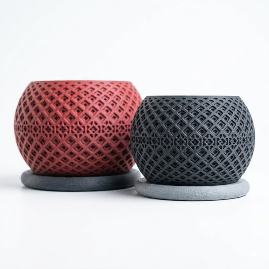 Alt Text (main hero image)
Vector Planter in two sizes — deep red and charcoal black — showing intricate diamond geometric lattice pattern on a spherical form with flat circular base — 3D printed indoor planter by Lux Print Labs
